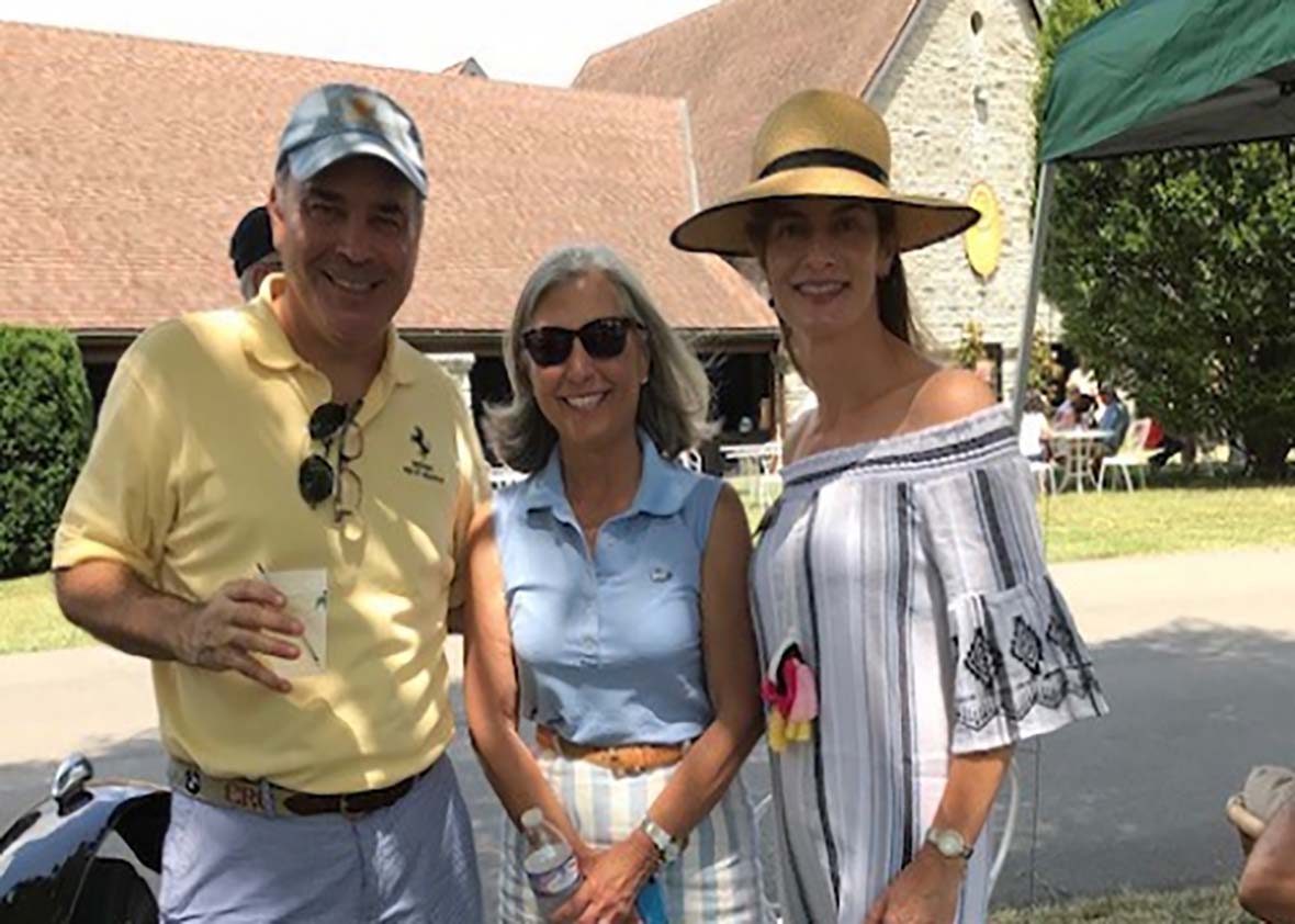 Three Dinsmore employees in a conference room with boxes and bags of canned food donations.