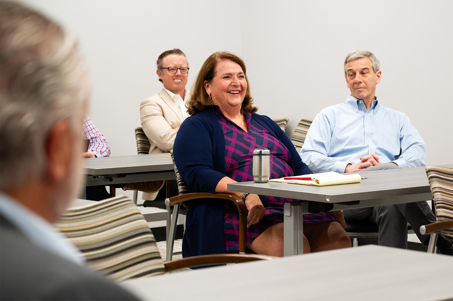 Woman in purple sitting in a meeting with two colleges.